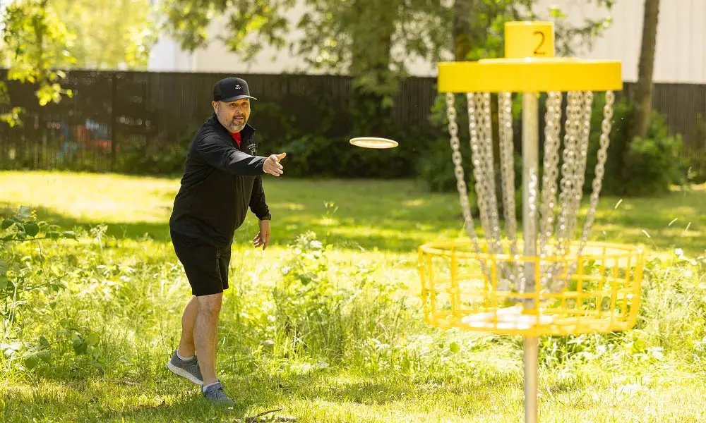 A player throws a disc at the Hole 2 basket on the Chemeketa disc golf course.
